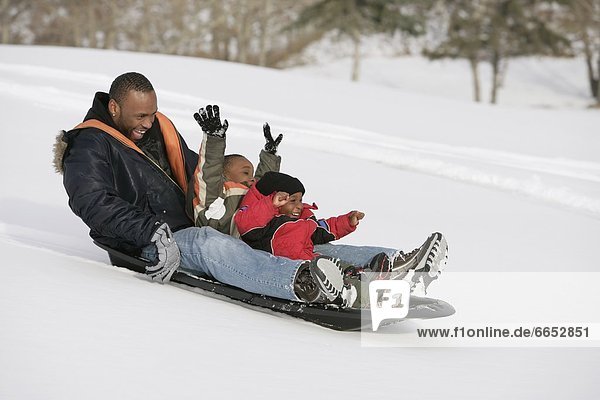 Father And Sons Sledding On Snow