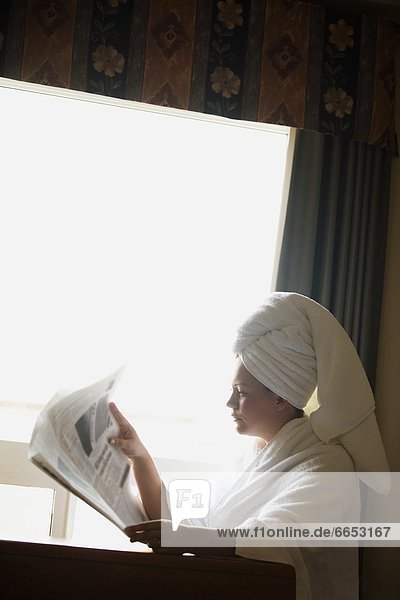 A Woman In A Bathrobe Reading The Newspaper