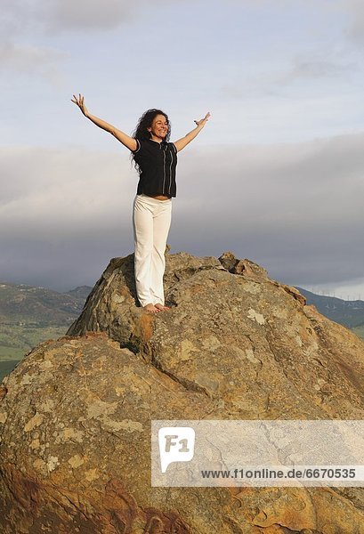 Woman On Mountain Peak With Arms Raised