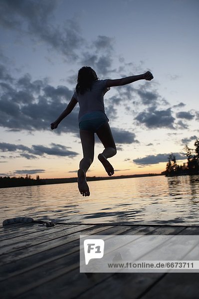 Girl Jumping Off A Dock Into The Lake