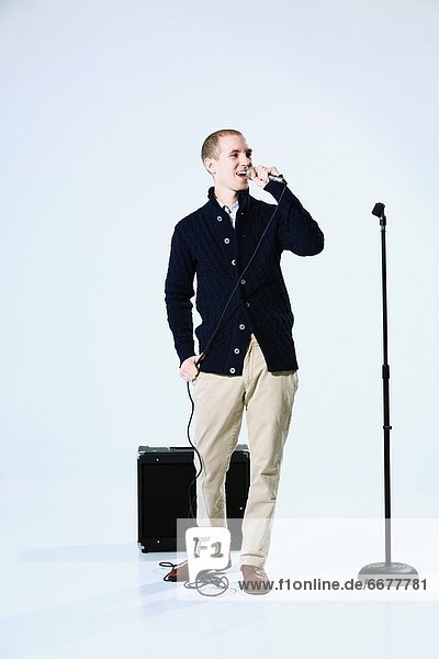 A Young Man Singing Into A Microphone