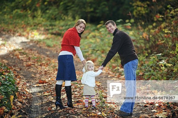 A Family Walking Down A Path In Autumn