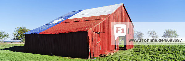 Red Barn in Field With Texas Flag on Roof