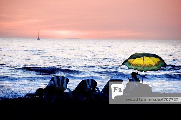 Silhouette Of Beach Chairs At Sunset