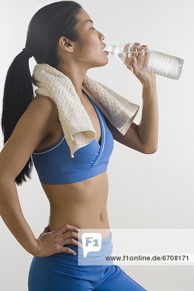 Frau trinkt Mineralwasser nach Training