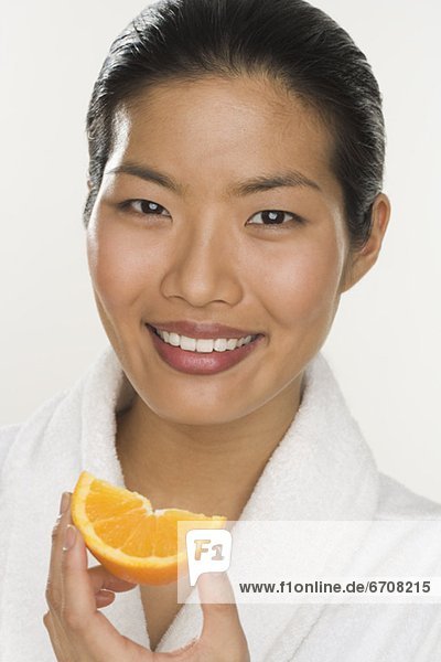 Portrait of a woman eating orange slice