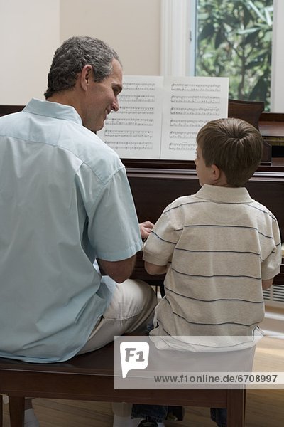 Menschlicher Vater  Sohn  Klavier  jung  spielen