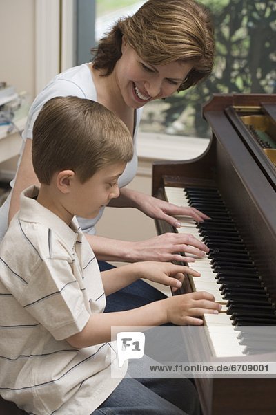 Mother and young son playing piano