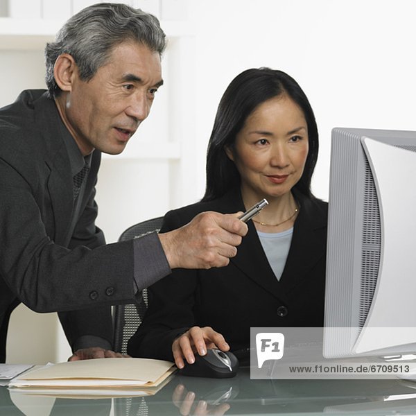 Asian businessman and businesswoman at computer