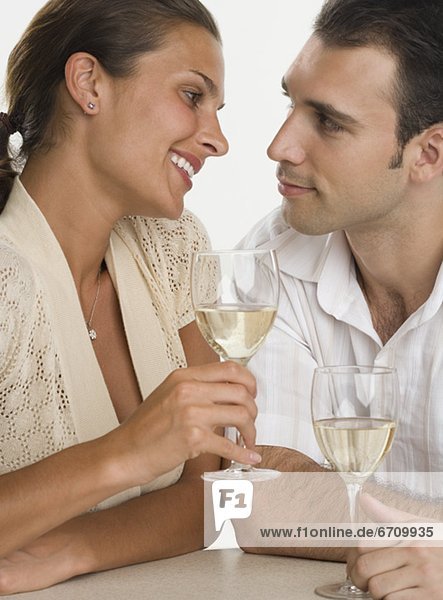 Couple smiling at each other and drinking wine