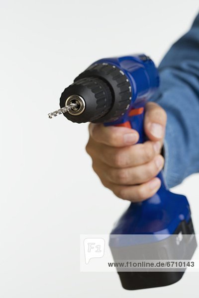 Close up studio shot of man holding cordless drill