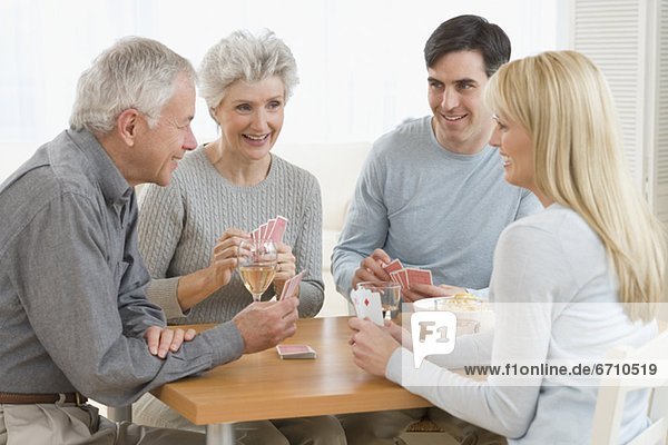 Senior couple and young couple playing cards
