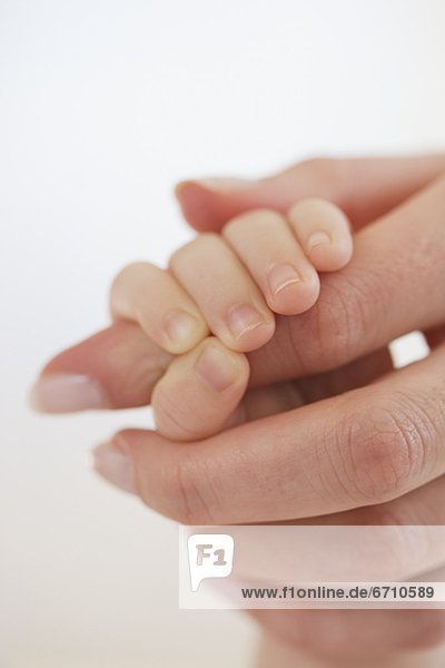 Close up of baby holding mother's hand