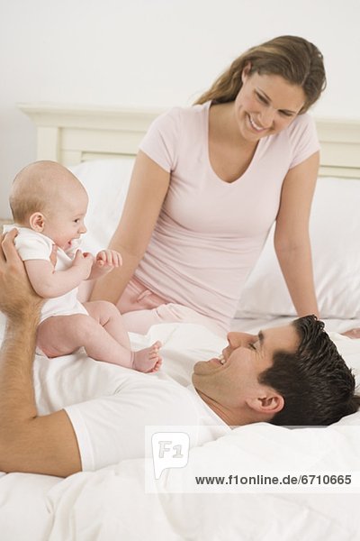 Parents playing with baby in bed