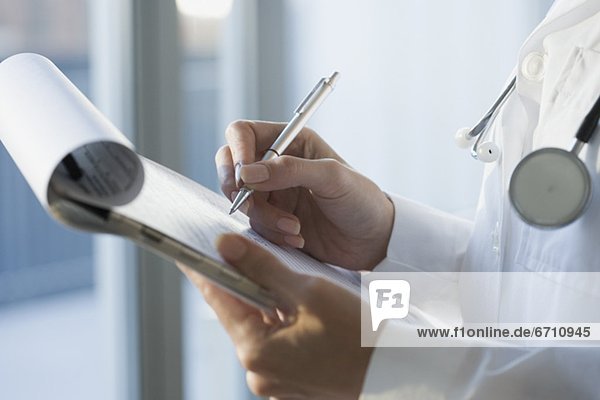 Close up of doctor writing on medical chart