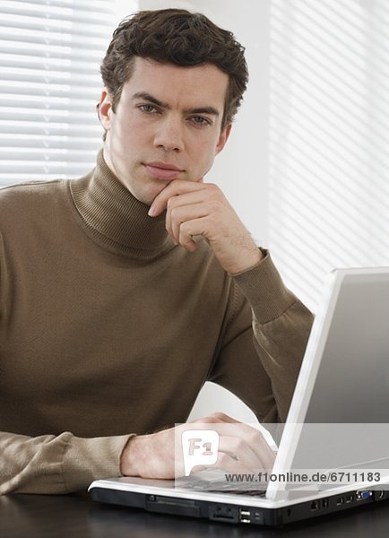 Portrait of businessman next to laptop