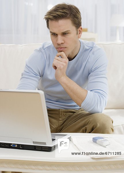 Man looking at laptop on sofa