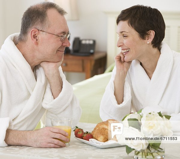 Couple in bathrobes smiling at each other