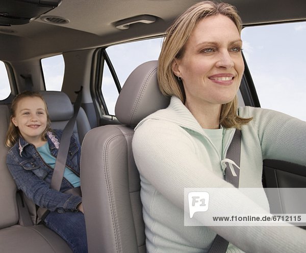 Mother driving car with daughter in back
