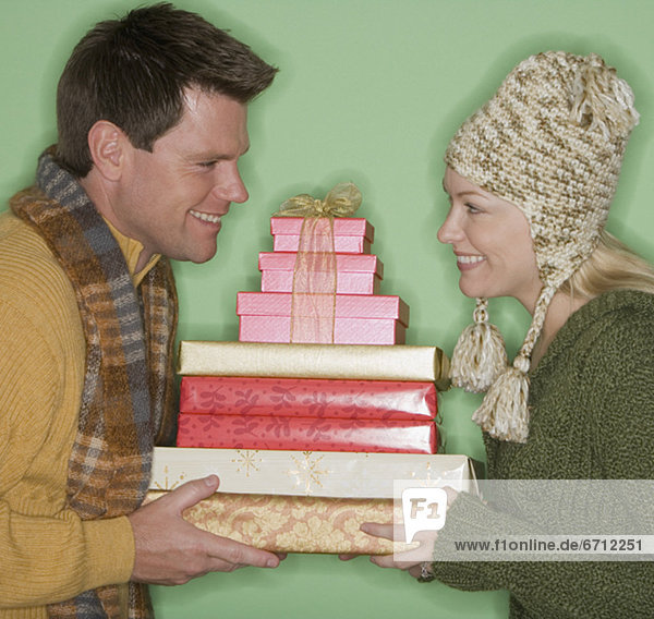 Couple holding stack of Christmas gifts