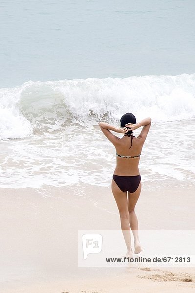 Frau  Bikini  Wasserwelle  Welle  Meer  jung  in die Augen sehen  ansehen  Angesicht zu Angesicht  gegenüber  Kleidung