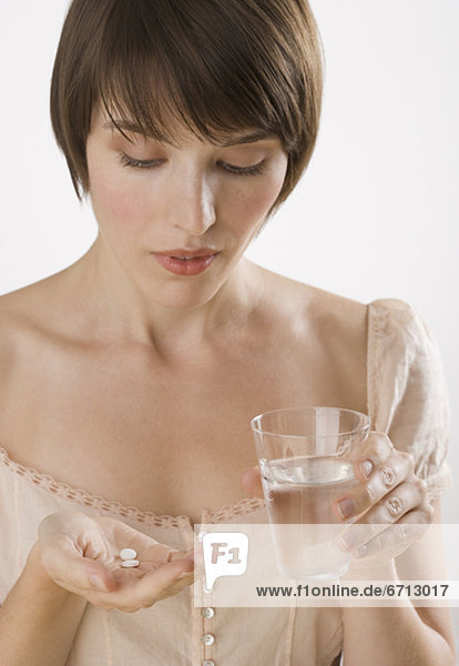 Frau nehmen Pillen mit Glas Wasser