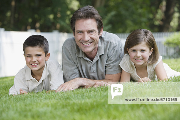 Father and children laying in grass