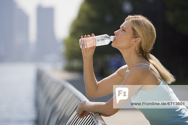 Frau trinkt aus Wasserflasche im Freien