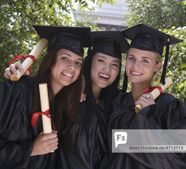 Female college graduates holding diplomas