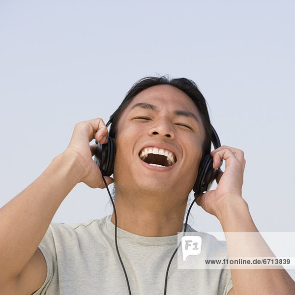 Asian man listening to headphones