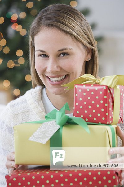 Woman holding pile of Christmas gifts
