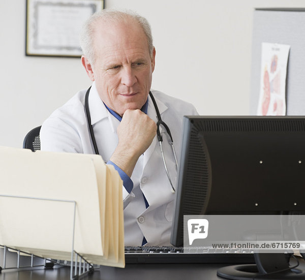 Senior male doctor looking at computer