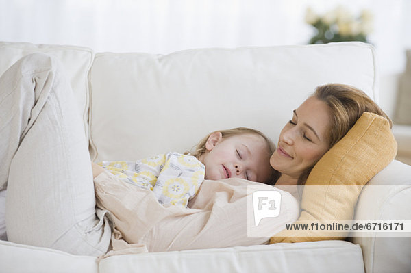 Mother and daughter sleeping on sofa