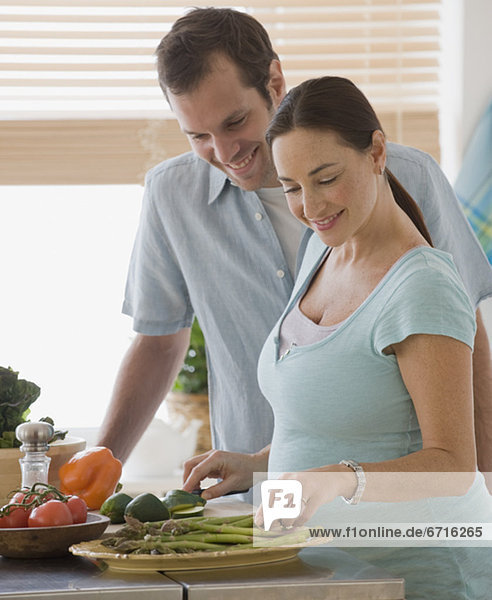 Pregnant Hispanic couple preparing food