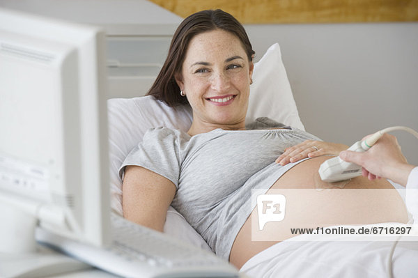 Pregnant Hispanic woman looking at ultrasound monitor