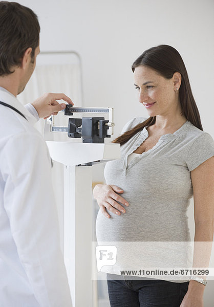 Pregnant Hispanic woman on scale in doctorÕs office