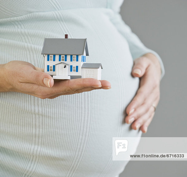 Pregnant woman holding model house