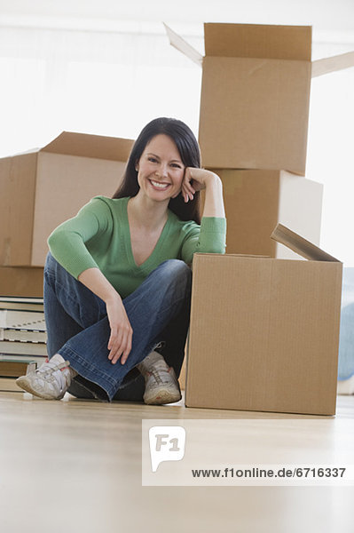 Woman leaning on moving box in new house