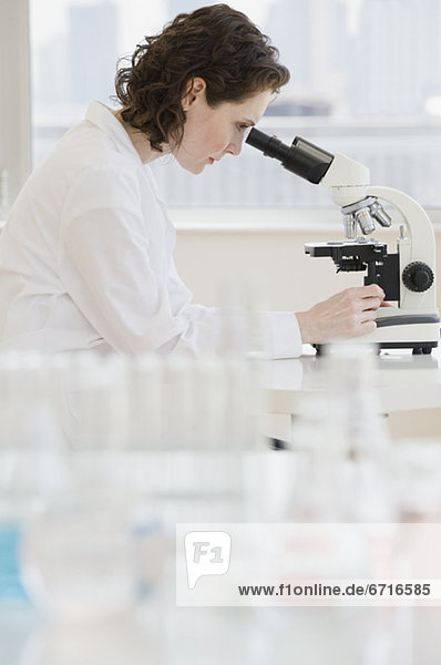 Weibliche Wissenschaftler schauen hinein Mikroskop