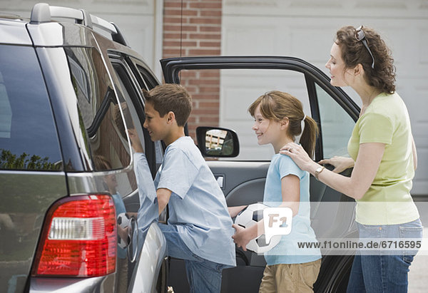 Mother and children getting into car with soccer ball