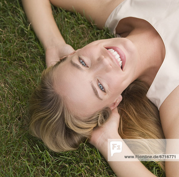 Woman laying in grass with hands behind head