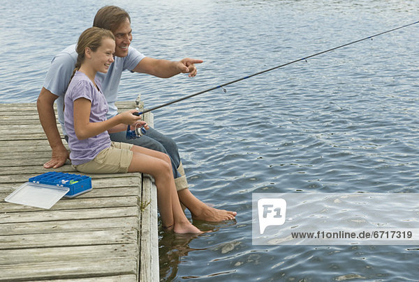 Father and daughter fishing off dock