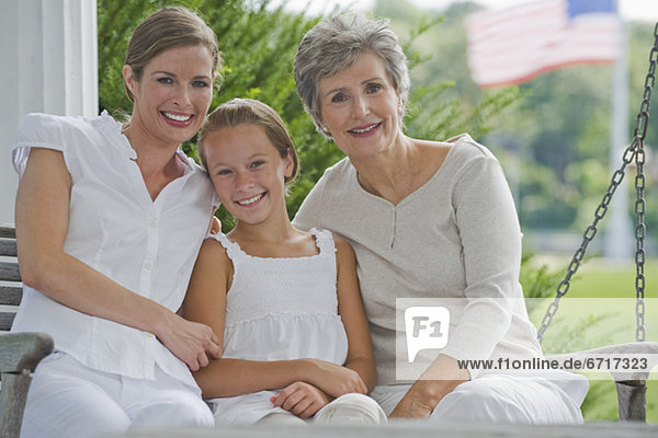 Three generations of women sitting on porch