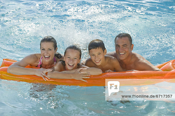 Family resting on raft in swimming pool