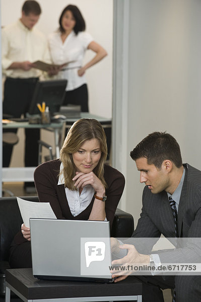 Businessman and businesswoman using laptop
