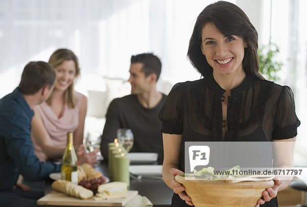 Portrait of woman holding salad bowl with friends in background