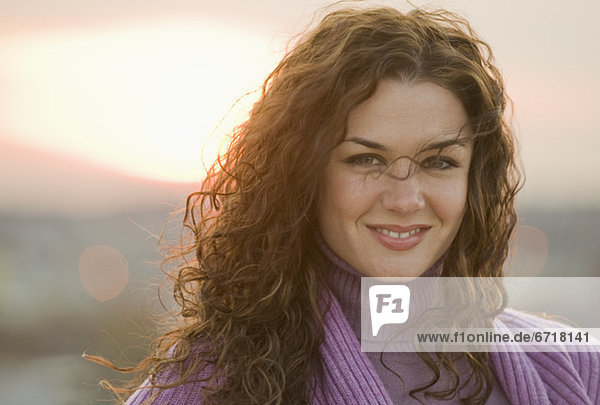 Portrait of smiling woman with sunset in background