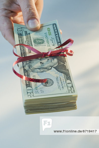 Man holding stack of money wrapped in ribbon