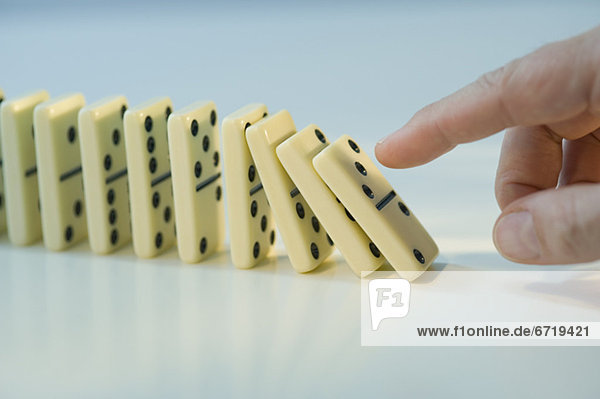Man pushing row of dominoes