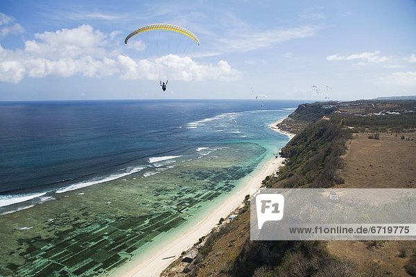 A Paraglider Soars Free Over The Cliffs And Beaches Of The Bukit Peninsula In Bali  Indonesia